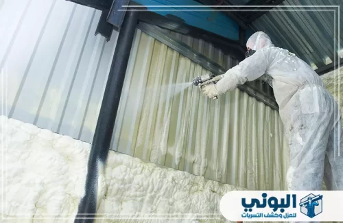 عزل فوم بالرش في الرياض 0500805875 البوني فني يرتدي بدلة حماية كاملة أثناء رش مادة الفوم الرغوي لعزل جدران من الطوب.