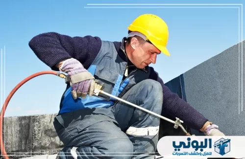 عزل أسطح خرسانية بالرياض 0500805875 البوني فني يرتدي معدات السلامة ويستخدم الحرارة لتركيب طبقات العزل.