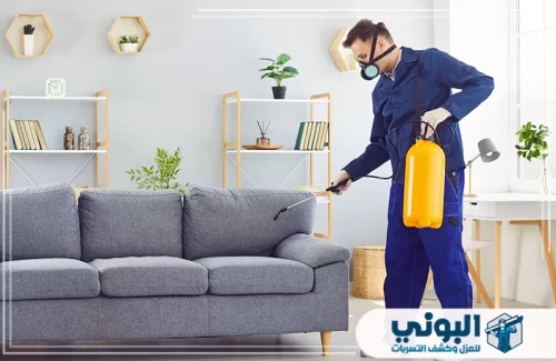رش مبيدات حشرية بالرياض 0500805875 البوني فني ببدلة زرقاء يرش الأريكة في غرفة معيشة عصرية.
