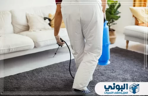 خدمات مكافحة الآفات بالرياض 0500805875 البوني فني ببدلة وقائية بيضاء يرش السجاد داخل المنزل.