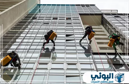 شركة تنظيف عمائر بالرياض 0500805875 شركة البوني تنظيف واجهة زجاجية مرتفعة عبر فريق عمل بالحبال يغطي المساحات الخارجية بدقة.