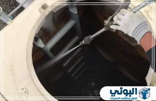 تنظيف خزانات الفيبر جلاس بالدمام 0500805875 شركة البوني عملية تنظيف خزان مياه من الداخل باستخدام مضخة مياه قوية لإزالة الرواسب، مع ظهور السلم الداخلي.