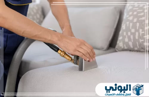 تنظيف كنب وسجاد بالدمام 0500805875 شركة البوني فني محترف يستخدم أداة الشفط العميق لتطهير أريكة رمادية وإزالة الغبار والبقع بدقة متناهية.